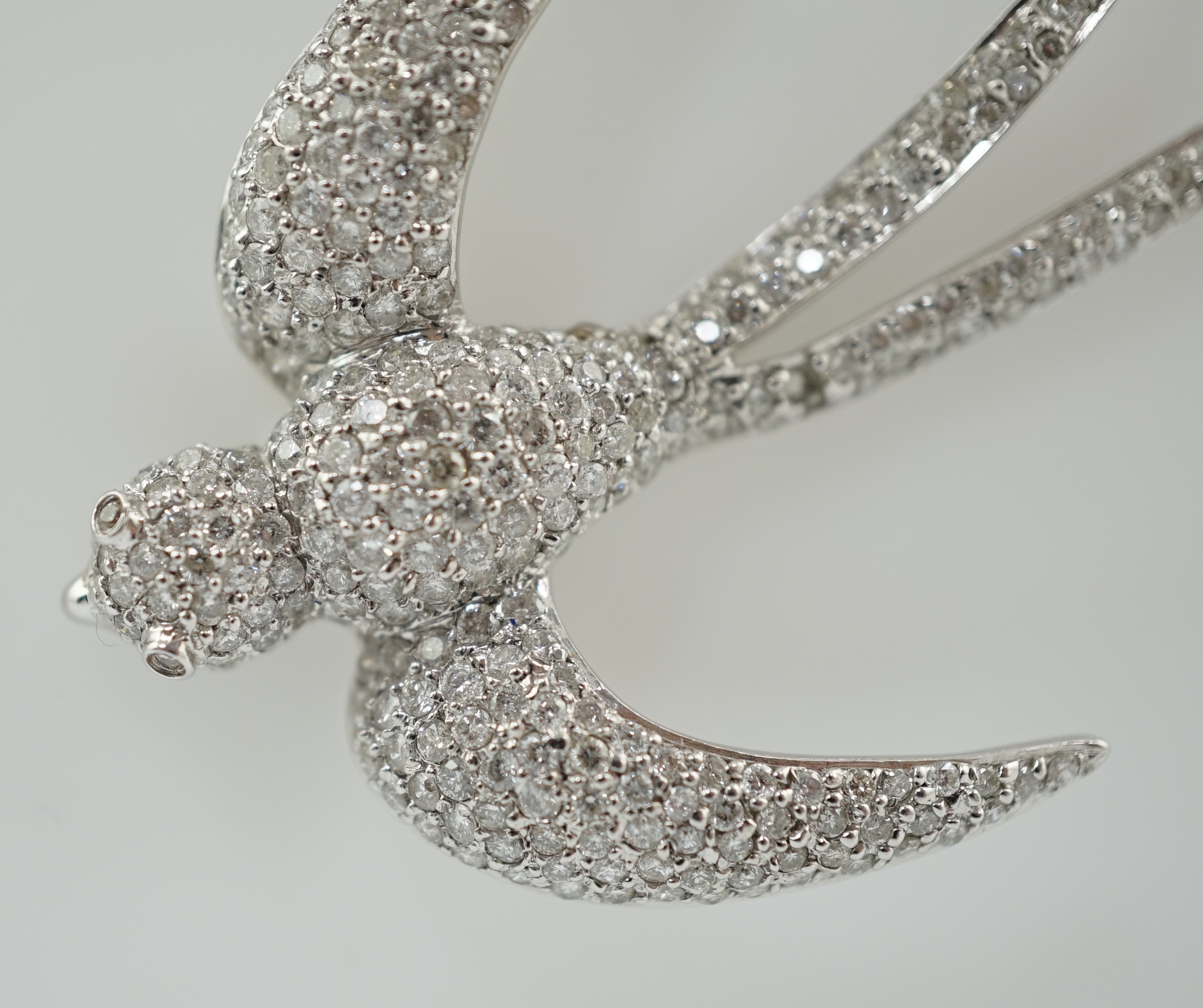 A modern 18k white gold and pavé set diamond pendant, modelled as a swallow, on an 18ct white gold fine link chain